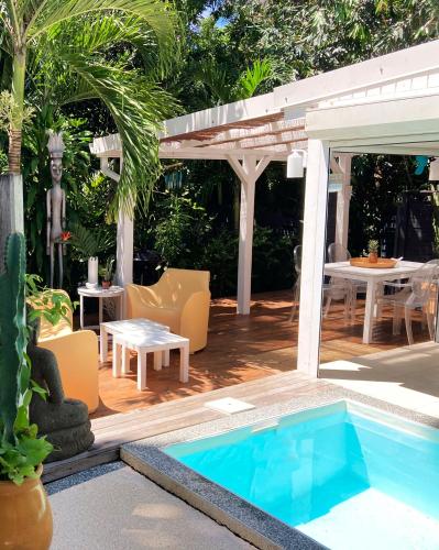 a backyard with a swimming pool and a pergola at 17 Les Palmes - Maison de charme - Piscine privée et accès plage in Sainte-Anne