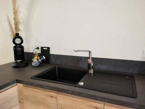 a kitchen counter with a black sink and a clock at LE MAZOT-SPA HIVER ET ETE-Piscine-Proche lac-Charme-Détente in Lathuile