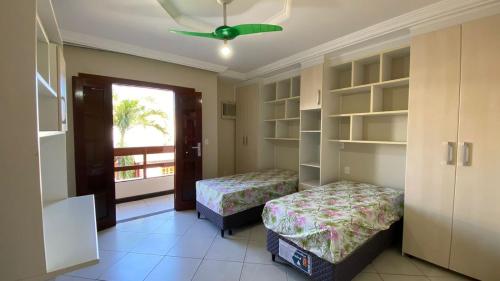 - une chambre avec 2 lits et un ventilateur de plafond dans l'établissement Casa Paris 481 - Sua Mansão na Praia do Morro, à Guarapari