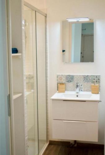 Baño blanco con lavabo y espejo en Joli trois chambres première ceinture Avignon en Aviñón