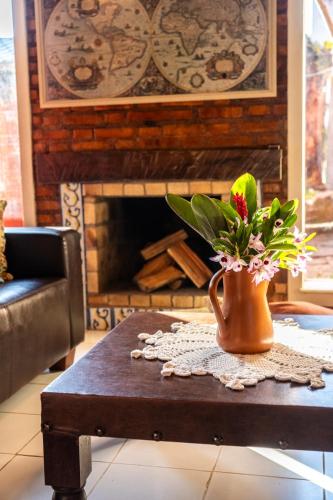 a vase with flowers on a table in front of a fireplace at Pousada Mar de Dentro in Florianópolis