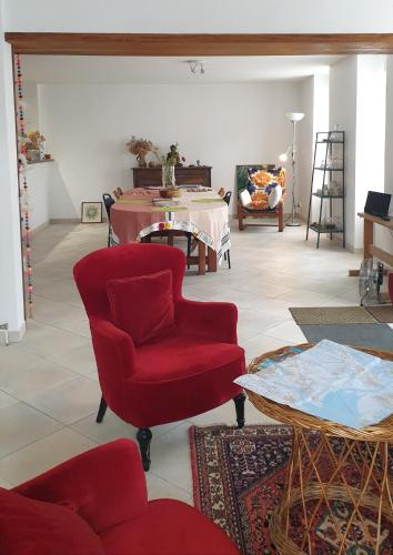 un salon avec une chaise rouge et une table dans l'établissement Balade en estuaire, à Nieulle-sur-Seudre