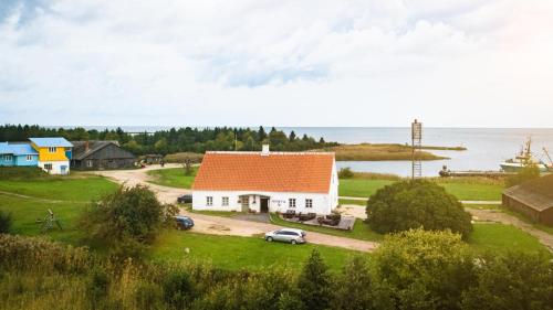 a white house with an orange roof on a hill next to the water at Ungru Guesthouse in Suuresadama