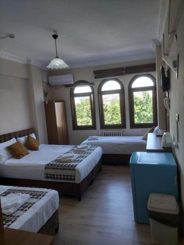 a hotel room with two beds and two windows at Biter Hotel in Istanbul