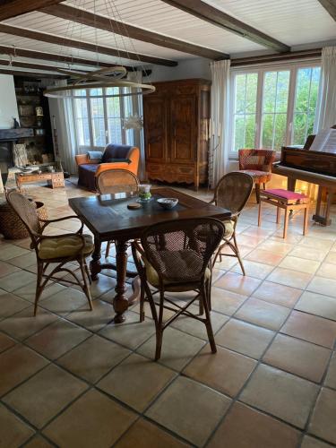 a living room with a table and chairs and a piano at La maison du petit bonheur in Moutier