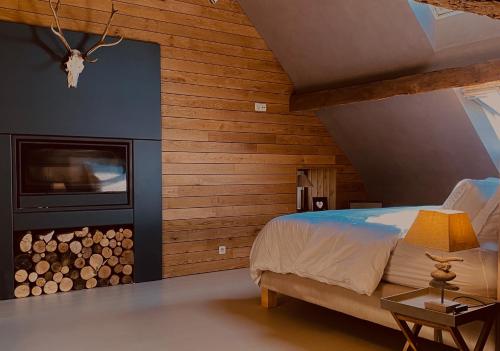 een slaapkamer met houten wanden en een bed met een open haard bij La Prairie in Herve