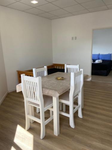 a dining room table with four white chairs at Complejo 599 in San Luis