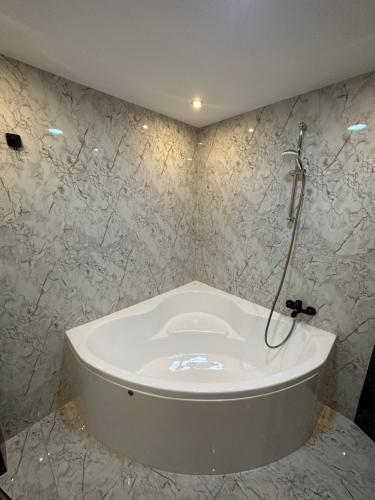 a white tub in a bathroom with marble walls at Modern Apartments Neuburg 3 - TOP NEU - 2 Zimmer, Komfort, Balkon, Wi-Fi, Smart TV, Badewanne, Küche in Neuburg an der Donau