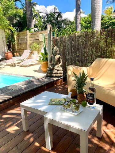 a patio with a table and a statue next to a pool at 17 Les Palmes - Maison de charme - Piscine privée et accès plage in Sainte-Anne