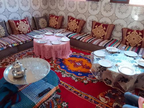 a living room with couches and tables on a rug at Dar Brahim tizgui nbarda in Ouarzazate