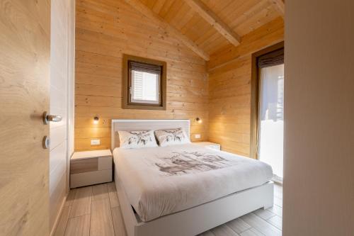 sypialnia z łóżkiem w drewnianej ścianie w obiekcie Ivan House w Livigno