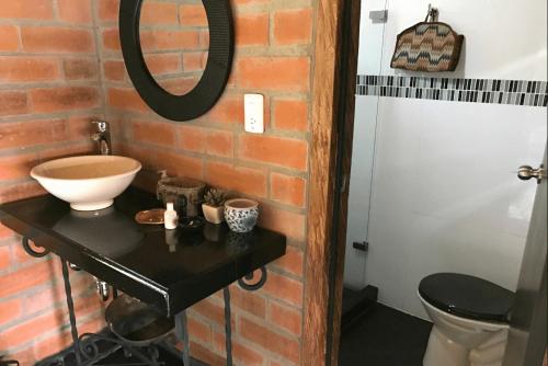 a bathroom with a sink and a toilet in a brick wall at Rancheria Loft Chalet, lago privado in Rionegro