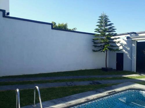 um quintal com piscina e uma árvore ao lado de um edifício em Casa Hogareña las estacas 