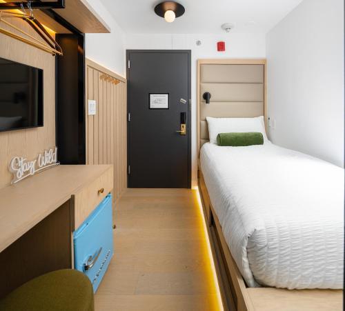 a small bedroom with a bed and a tv and a door at Little Charlie Hotel in New York