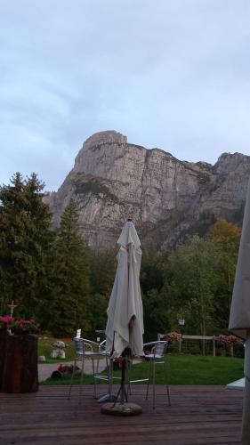 an umbrella and chairs with a mountain in the background at Rifugio La Montanara in Molveno