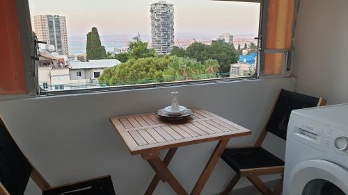 Gil's Home of Joy & Serenity في حيفا: طاولة خشبية صغيرة في غرفة مع نافذة