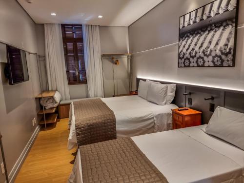 ein Hotelzimmer mit 2 Betten und einem Stuhl in der Unterkunft Mosteiro Hotel de Charme próximo ao Vale dos Vinhedos in Garibaldi
