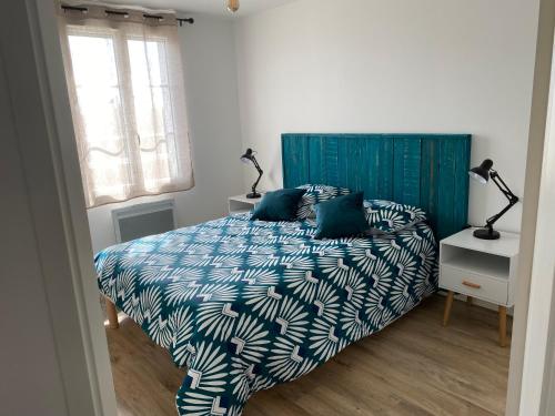 1 dormitorio con 1 cama con edredón azul y blanco en Entre plage et marais, en Bourcefranc