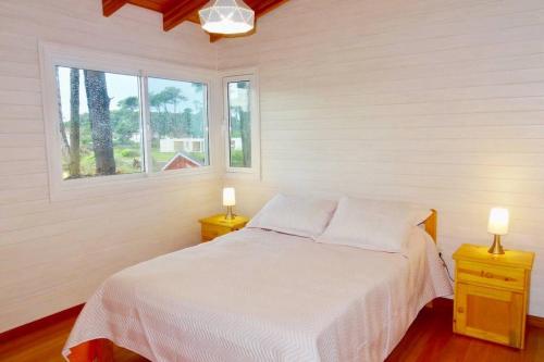 um quarto com uma cama branca e duas mesas de cabeceira em Klimatisiertes Haus am Meer in Chihuahua em Punta del Este