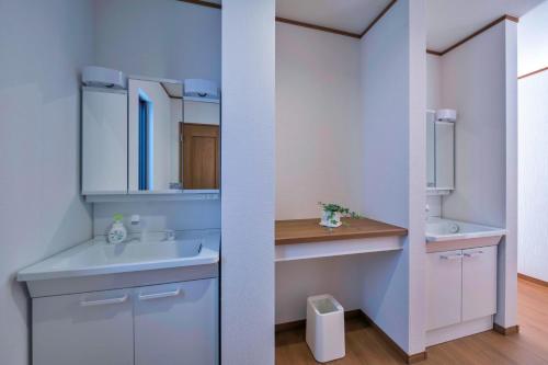 La salle de bains blanche est pourvue d'un lavabo et d'un miroir. dans l'établissement White Terrace A - Vacation STAY 42837v, à Nakadomari