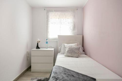 a white bedroom with a bed and a window at Habitaciónes bonitas y cómodas in Hospitalet de Llobregat