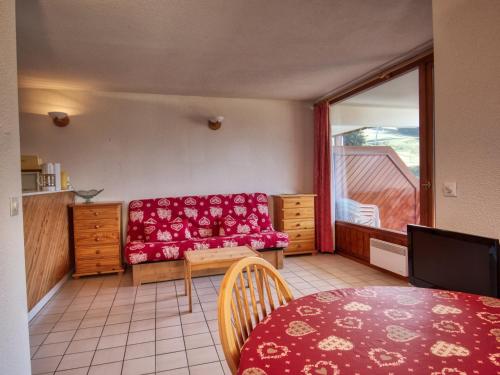 a living room with a red couch and a table at Appartement Morillon 1100, 3 pièces, 6 personnes - FR-1-642-37 in Morillon