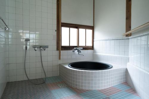 a bathroom with a tub with a shower and a window at Setouchi base - Vacation STAY 48109v in Mitoyo