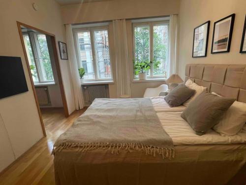 a large bed in a room with windows at Central lux location, self check-in, ensuite with full kitchen in Helsinki