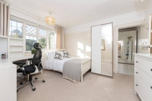 a bedroom with a bed and a chair and a mirror at Rose Garden House in Luton