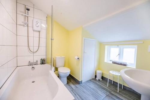 a bathroom with a tub and a toilet and a sink at No. 10, The Cottage in Framlingham