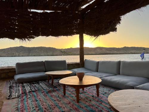 a living room with a couch and tables in front of the water at Ayujidda Nubian House in Aswan
