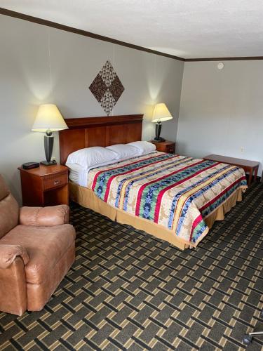ein Hotelzimmer mit einem Bett und einem Stuhl in der Unterkunft Bedford Inn in Elk City