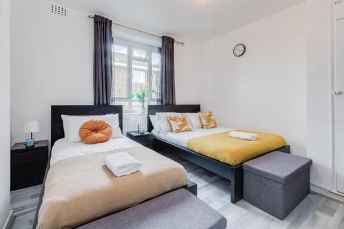 a bedroom with two beds and a ottoman in it at Deluxe 1 Bed Apartment - Battersea, Nine Elms & Vauxhall in London