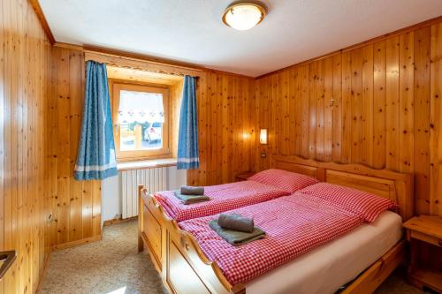 een slaapkamer met een bed in een houten kamer bij Bait Di Farina - Trepalle in Livigno