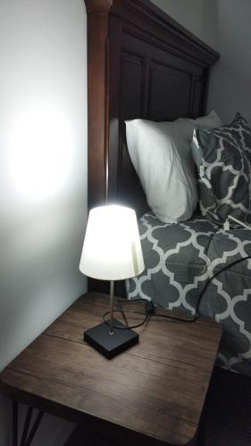 a lamp on a wooden table next to a bed at Lovely and Peaceful Home in Guatemala