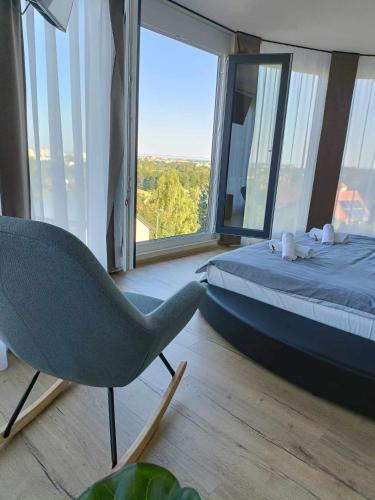 a bedroom with a bed and a chair and a window at WEST Panorama Penthouse - apartment with a fantastic view of the city in Szombathely