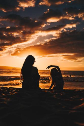 a couple sitting on the beach watching the sunset at Casa Amigos - By Pura Villas in Dominical
