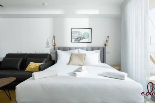 a bedroom with a large white bed and a couch at דירת סטודיו מעוצבת 50 מטר מהים - By Edomlux in Eilat