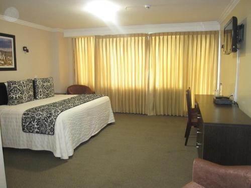 a hotel room with a bed and a desk at Hotel Novalux in Ambato