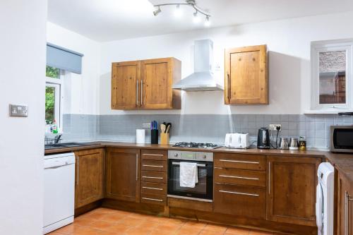 cocina con armarios de madera y horno con fogones en Mapperley Park Guesthouse, en Nottingham