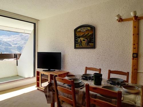 une salle à manger avec une table, une télévision et une fenêtre dans l'établissement Studio duplex agréable Au pied des pistes Balcon - FR-1-344-921, aux Menuires