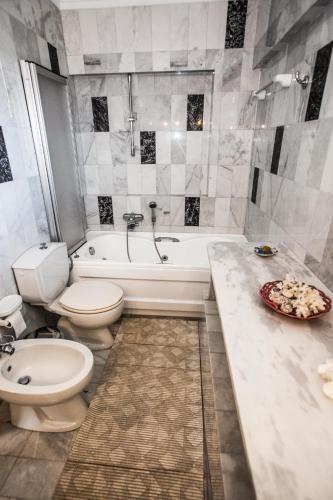 a bathroom with a toilet and a tub and a sink at Pontinos Villa in Myloi