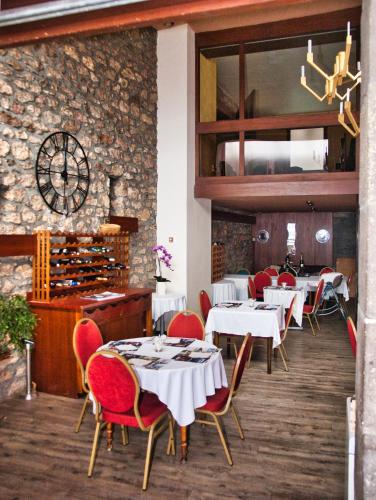 a restaurant with white tables and red chairs at Hôtel de Paris in Châtel-Guyon