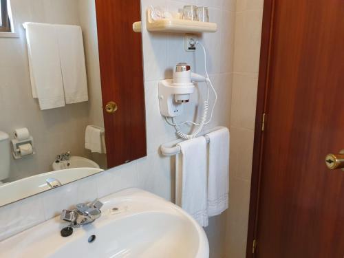 y baño con lavabo blanco y espejo. en Hotel Peninsular, en Monte Real