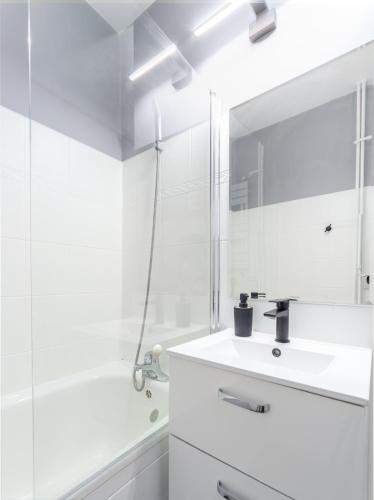 a white bathroom with a sink and a mirror at Millenium Apartment Self check-in Faktura in Rzeszów