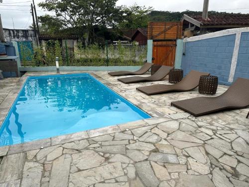 a swimming pool with lounge chairs in a backyard at Vila Maui in Ubatuba