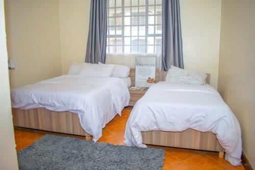 2 camas en una habitación con ventana en Zani Suites, en Nakuru