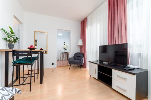 uma sala de estar com uma televisão e uma mesa e cadeiras em Millenium Apartment Self check-in Faktura em Rzeszów