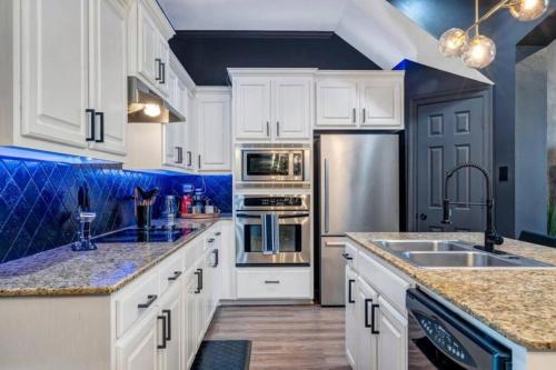una cocina con armarios blancos y electrodomésticos de acero inoxidable en Stylish & Romantic Home, Long-term friendly, King en Baton Rouge