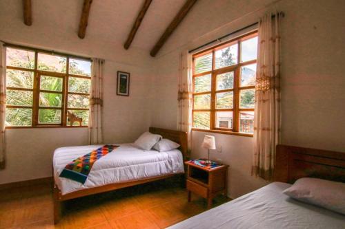 a bedroom with two beds and two windows at Eco Hacienda Roman in Machu Picchu